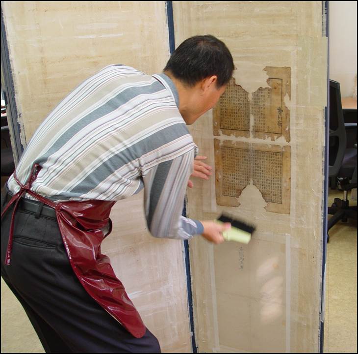 들대를 이용하여 배접지와 접착된 책지를 들어 말림판에 부착하는 사진