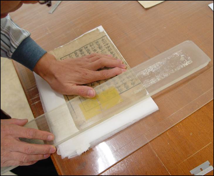 판심과 가재단된 책 밑쪽을 중심으로 절반으로 접어주는 사진