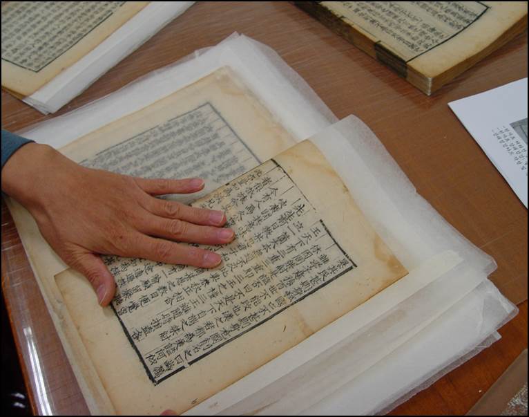 판심과 가재단된 책 밑쪽을 중심으로 절반으로 접어주는 사진